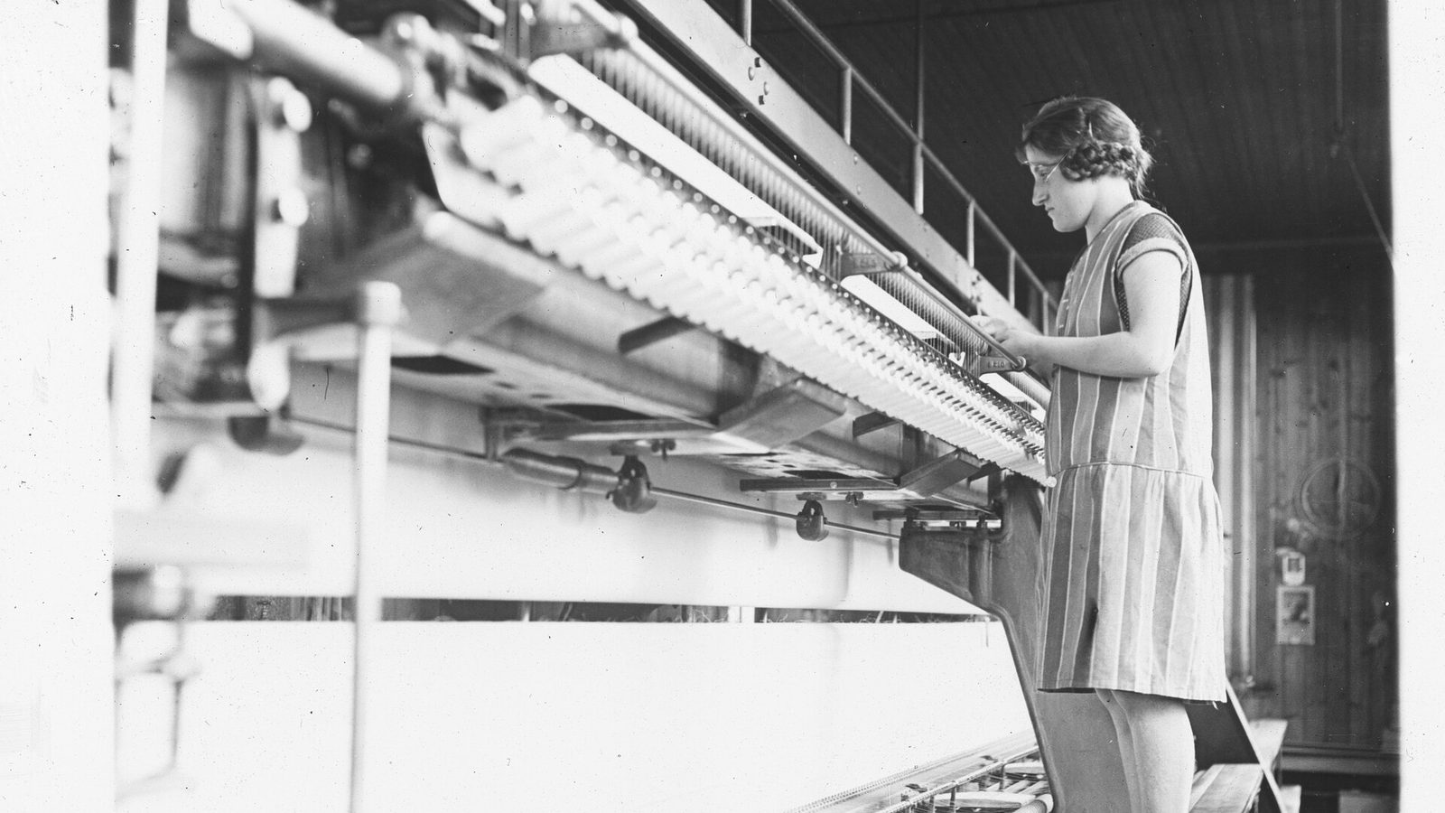 St. Gallen embroidery worker inspecting fabric at a schiffli embroidery machine, historical photo