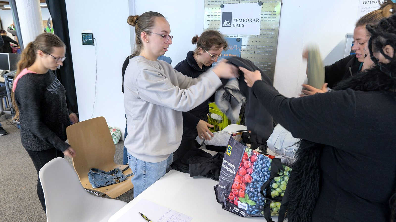 People bringing bags of old clothes to a community clothes swap