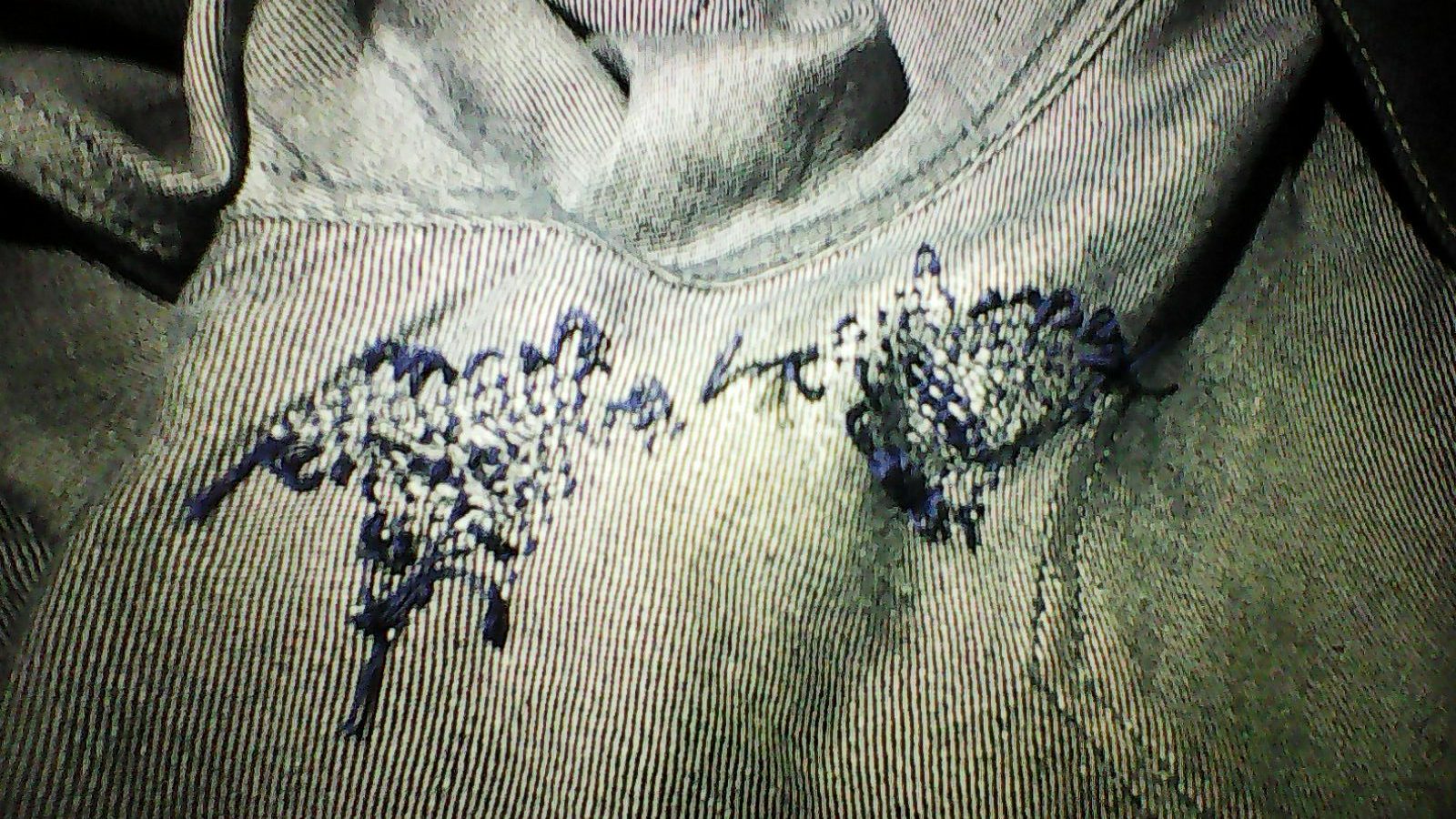 Inside of a pair of jeans showing hand-stitched visible mending over worn areas